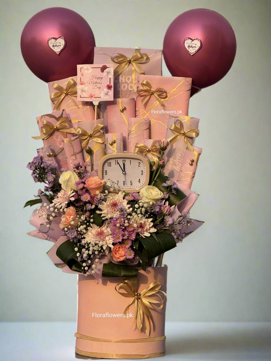 A gift arrangement featuring an assortment of items including roses, chrysanthemums, baby's breath, a clock, balloons, and chocolate.