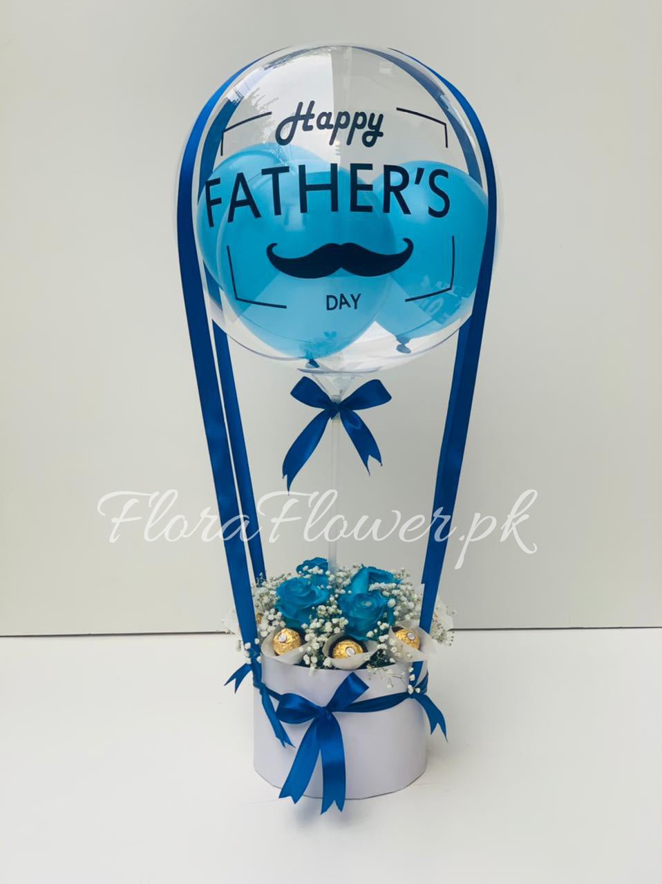 A gift arrangement featuring 9 Ferroro Rocher chocolates and a customized balloon with 'Happy Father's Day' text, all decorated with blue ribbons.
