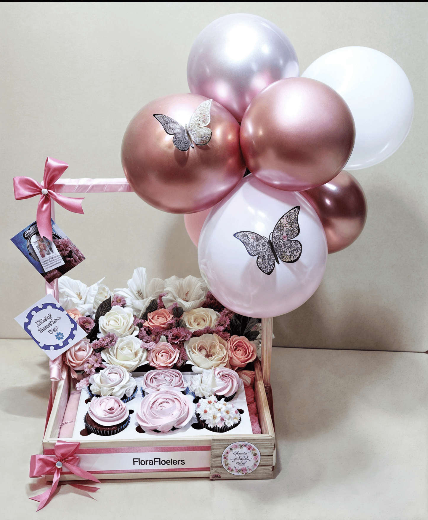 Decorative arrangement with balloons, flowers, and cupcakes on a light background