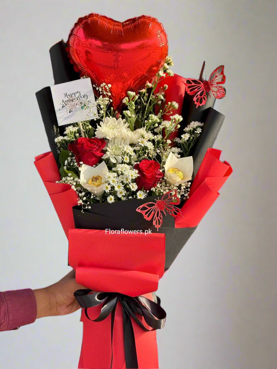 Bouquet of flowers with a heart-shaped balloon and a card, held by a person.