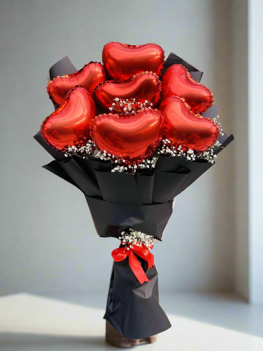 A bouquet of red heart-shaped balloons with Baby's Breath Premium wrapping sheets, presented against a metallic background.