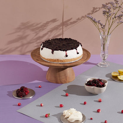 Decorative cake on a wooden stand with berries and lemons on a multicolored background. Send flowers to islamabad. send flowers to pakistan