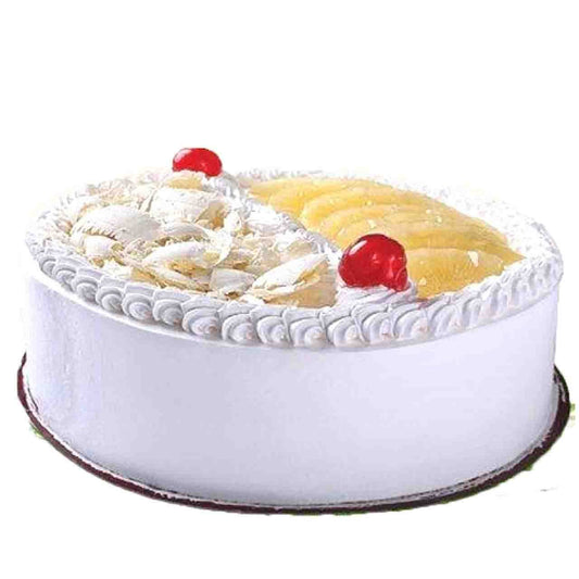 Decorative cake with white frosting, pineapple slices, and red cherries on a white background