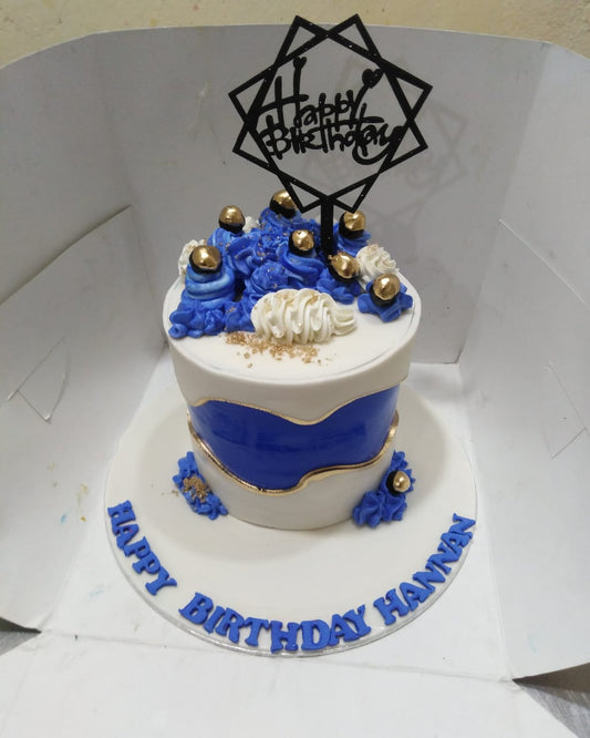 Birthday cake with blue and white design, gold accents, and 'Happy Birthday Hannan' text.