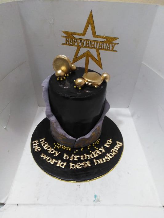 Black birthday cake with gold decorations and 'Happy Birthday' to the world best husband text