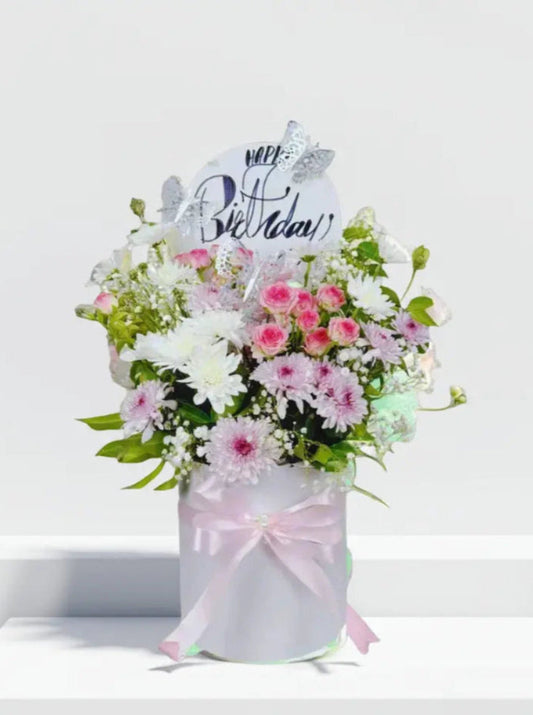 Floral arrangement in a box with a 'Happy Birthday' card on a white background