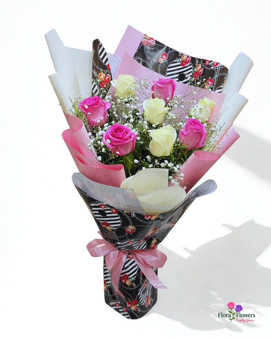 Bouquet of pink and white roses wrapped in decorative paper with a pink ribbon on a white background.