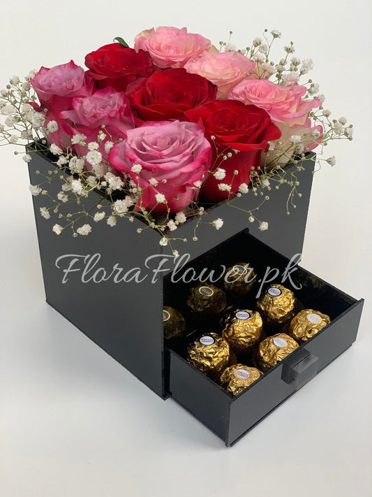 A box of roses with a drawer containing chocolate candies.