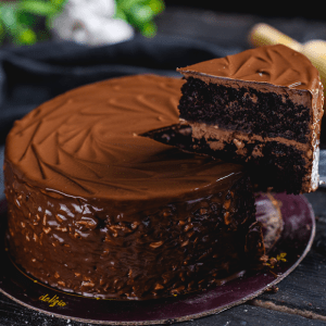 Chocolate cake with a slice taken out on a dark surface
