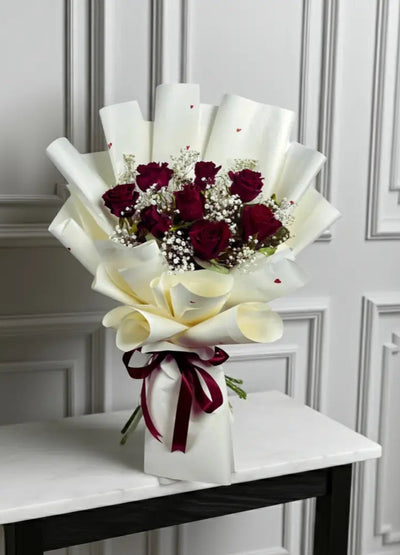 Bouquet of red roses and white calla lilies on a marble table with a white wall background. Send flowers to lahore. send flowers to Pakistan