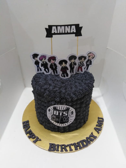 BTS-themed birthday cake with character toppers and decorative elements on a white background