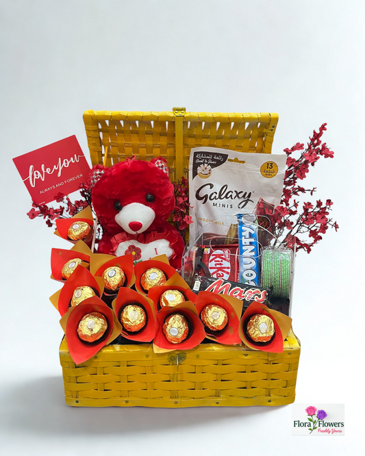 Gift basket with teddy bear, chocolates, and snacks on a white background