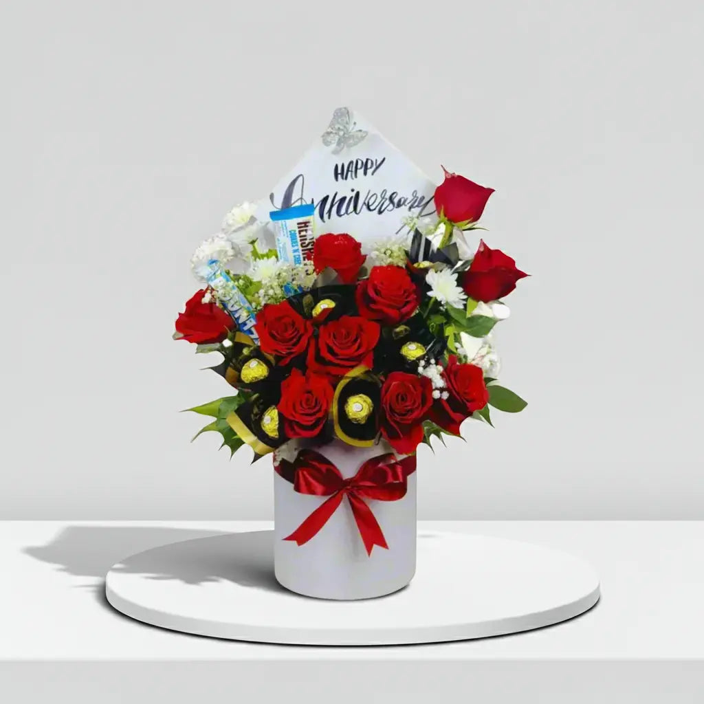 Bouquet of red roses with a 'Happy Anniversary' card on a white background