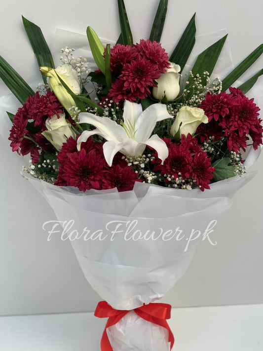 A bouquet of flowers including red roses, white chrysanthemums, a white lily, and baby's breath, wrapped in premium wrapping paper with a red ribbon.