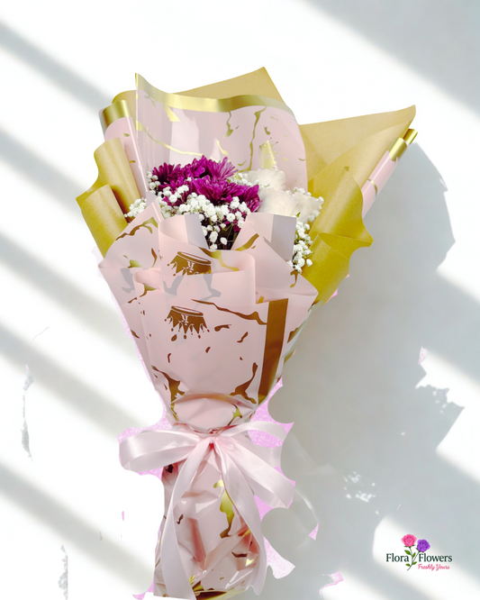 Bouquet of flowers wrapped in pink paper with gold accents on a white background