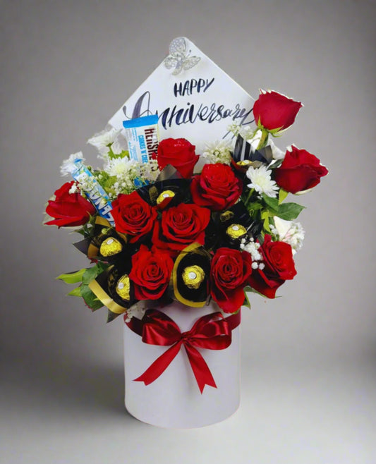 Bouquet of red roses with a 'Happy Anniversary' card on a white background