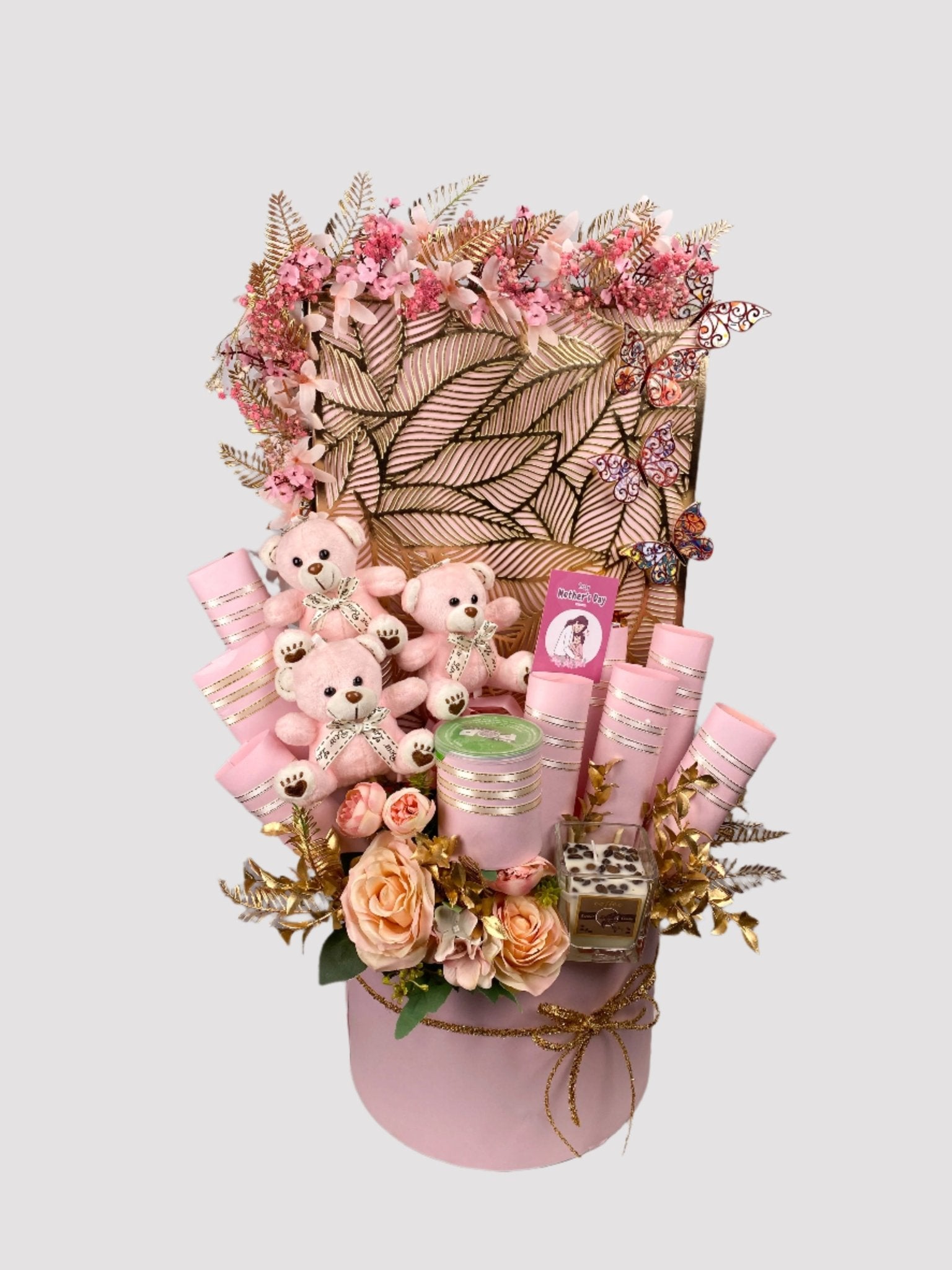 A gift basket arrangement featuring an assortment of chocolate bars and teddy bears, adorned with artificial flowers and a fragrance candle.