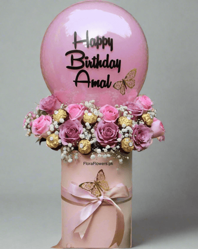A birthday balloon with 'Happy Birthday Amal' printed on it, accompanied by an arrangement of pink roses, baby's breath, and chocolates. Send flowers to islamabad. send flowers to pakistan