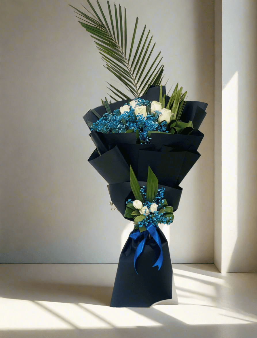 A bouquet of flowers with blue and white flowers, wrapped in black paper with a blue ribbon.