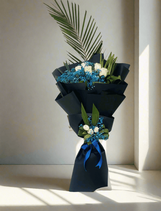 A bouquet of flowers with blue and white flowers, wrapped in black paper with a blue ribbon.