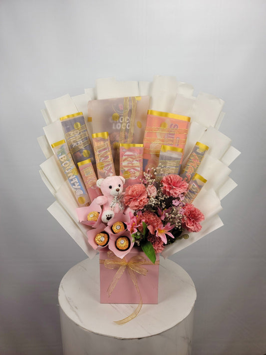 Bouquet with flowers, a teddy bear, and wrapped candies on a white pedestal against a gray background.