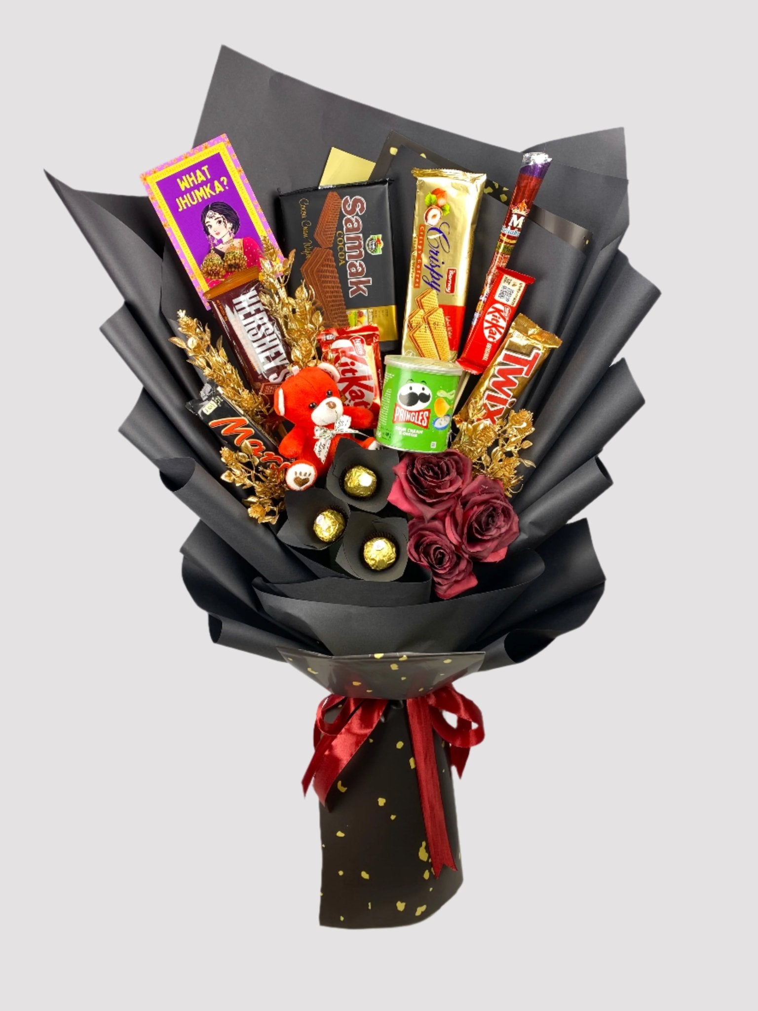 A bouquet arrangement featuring an assortment of chocolate bars and candies, with decorative elements such as Twix, Kitkat, Mars, and Hershey's, presented with artificial flowers and adorned with red ribbon.