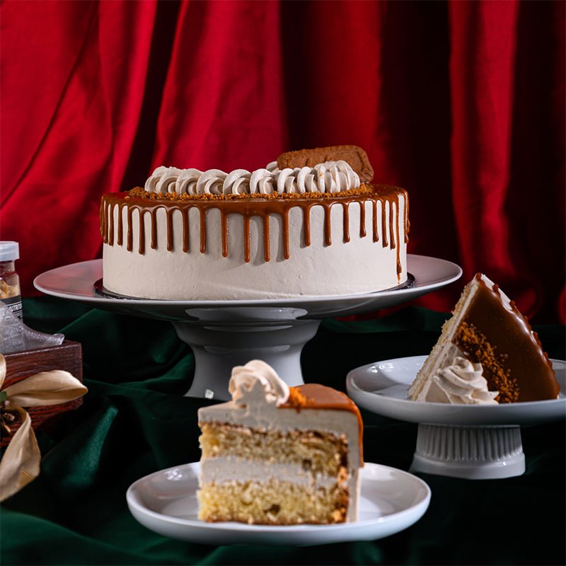 Decorative cake with caramel drizzle on a stand against a red curtain background. Send flowers to islamabad. send flowers to pakistan