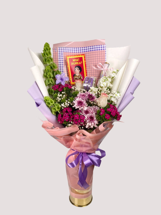 A bouquet of fresh flowers, including roses and chrysanthemums, with a pair of earrings and a mehndi design, wrapped in paper with a pink ribbon.
