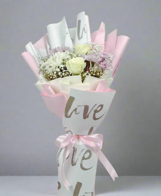 Bouquet of flowers wrapped in paper with 'love' text on a pink background